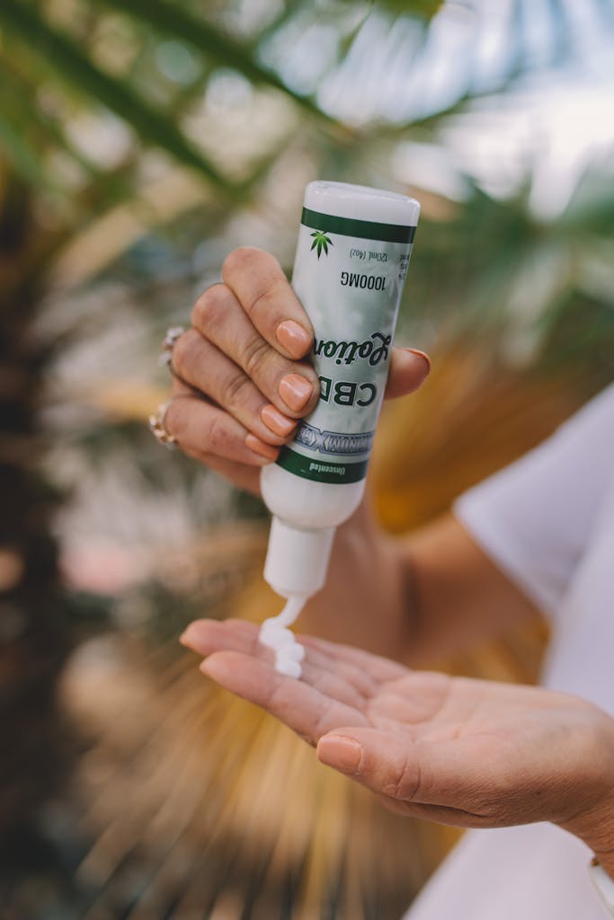 Close-up of hands applying CBD lotion outdoors, emphasizing skincare and relaxation.