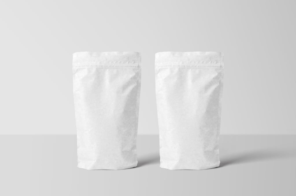 Two white paper stand-up pouches for packaging mockup on a clean surface.